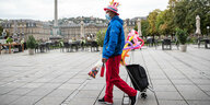 Ein Ballonkünstler zieht in bunten Kleidern über den fast leeren Schlossplatz in Stuttgart