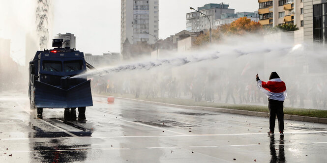 Eine einzelne Person wird von einem Wasserwerfer angesprüht.