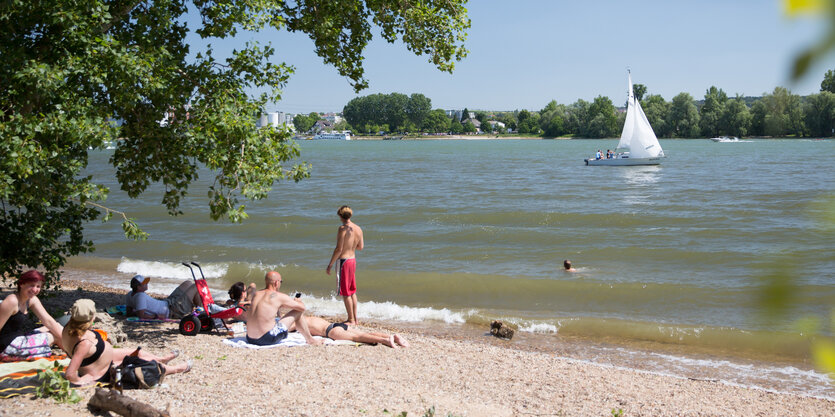 Menschen an einem Strand an einem Fluss.