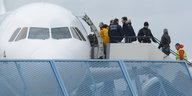 Abgelehnte Asylbewerber werden in ein Flugzeug geführt