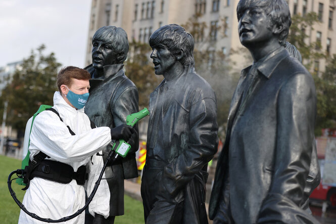 Ein Arbeiter desinfiziert die Statue der Beatles.