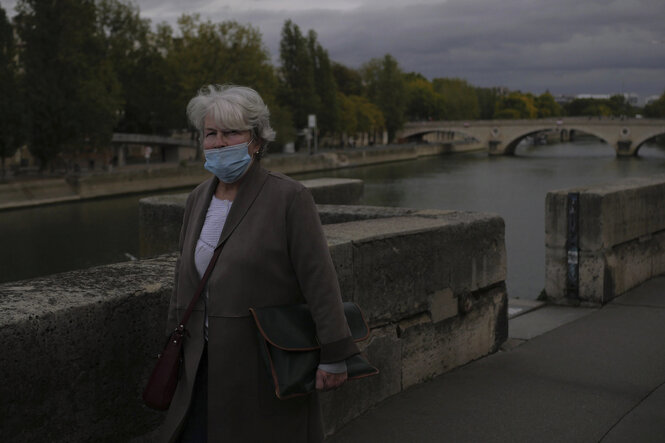 Eine Frau mit Mundschutz an einem Fluss.