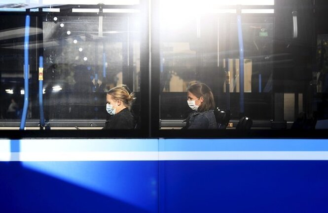 Menschen sitzen im Bus und tragen eine Mund-Nasen-Maske