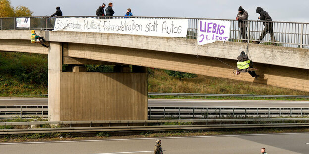 Hessen, Idstein: Umweltaktivisten hängen an einer Brücke über der Autobahn 3 und protestieren gegen die Rodung von Bäumen im Herrenwald und Dannenröder Forst bei Stadtallendorf im Zusammenhang mit dem geplanten Ausbau der Autobahn 49.