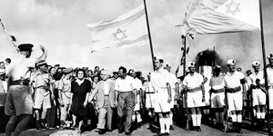 Ben Gurion inmitten von Menschen und zwei israelischen Fahnen