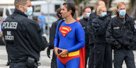 Ein Mann in Supermankostüm umringt von Polizisten.