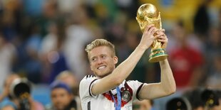 Fußballnationalspieler Andre Schürrle hält 2014 den WM-Pokal hoch