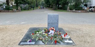 Blumen liegen vor einer echlichten Betonstele auf dem Oranienplatz