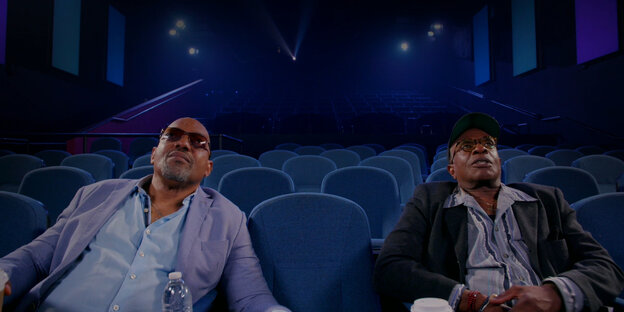 Die schwarzen Schauspieler Ken Foree und Keith David sitzen in „Horror Noire“ in einem leeren Kinosaal und schauen sich schwarzen Horror auf der Leinwand an