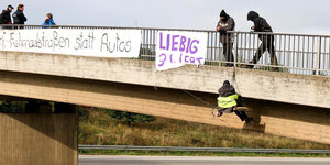 Eine Person seilt sich mit Transparenten an einer Brücke ab.