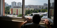 Ein Mann blickt am in Berlin aus einem Fenster im elften Stock eines Hochhauses über Wohnblocks im Stadtteil Marzahn