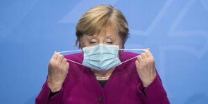 Angela Merkel setzt sich einen Mundschuztauf