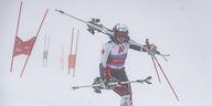 Eine Skifahrerin trägt im Nebel ihre Skier auf den Schultern