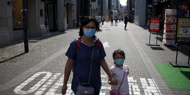 Eine Frau mit einem kleinen Kind, beide tragen Atmenschutzmasken