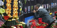 Blumen und Bilder zu Ehren der Todesopfer von Odessa. Ein Mann küsst eines der Bilder