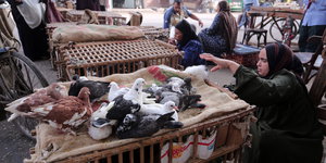 Eine Frau greift nach Tauben auf einem Markt