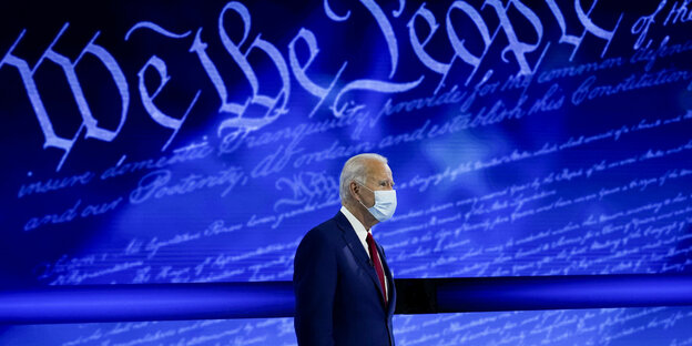 Joe Biden mit Maske vor einer blauen Wand