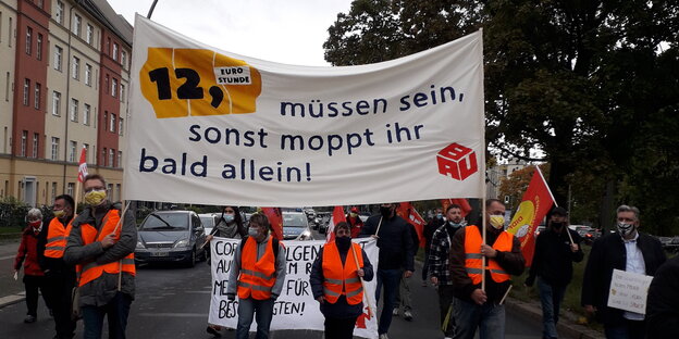 Demonstrierende halten ein Banner hoch, auf dem steht: "12 Euro müssen sein, sonst mobbt ihr bald allein"