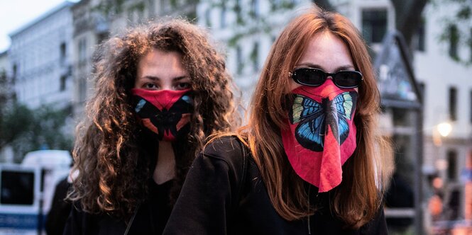 Zwei Frauen mit Mundschutz mit Schmetterlingsaufdruck.