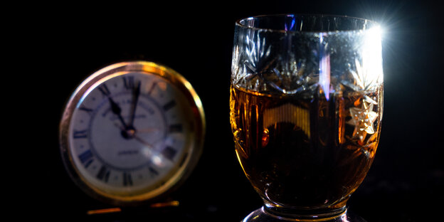 Ein Glas und eine Uhr, deren Zeiger auf 11 Uhr steht.
