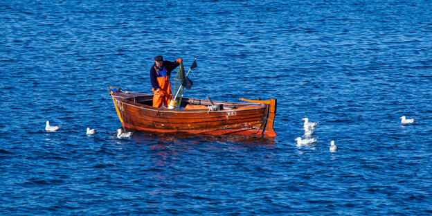 Ein Fischer leert auf der Ostsee zwischen den Inseln Rügen und Hiddensee in einem kleinen Holzboot seine Fangreusen
