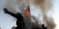 Ein Feuerwehrmann steht vor der Kirche Parroquia de La Asunción, die in Flammen steht