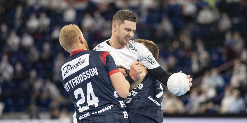 Flensburgs Jim Gottfridsson, Kiels Hendrik Pekeler und Flensburgs Magnus Rod ringen um den Ball.