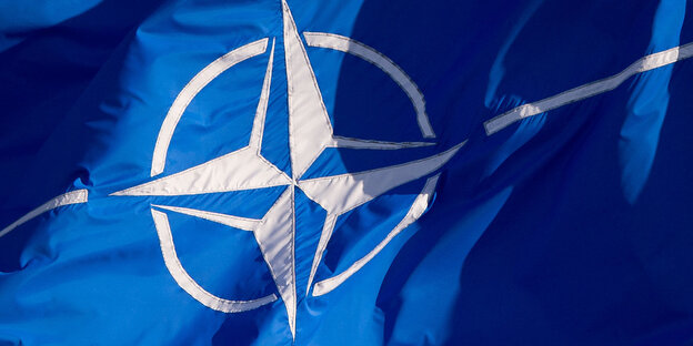 Detailaufnahme einer blauen Fahne mit dem Logo der Nato