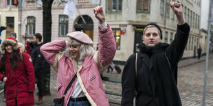 Zwei Demo-Teilnehmer:innen heben die linke Faust