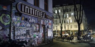 Eine nächtliche Aufnahme: Angeschlossene leere Tische und Stühle stehen vor dem Kino Intimes im Stadtteil Friedrichshain