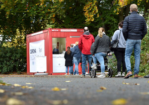 Nordrhein-Westfalen, Wuppertal: Menschen stehen in einer langen Schlange vor dem Eingang eines neuen Corona Walk-In-Testzentrums auf einem Parkplatz.