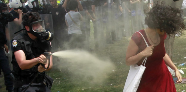 Polizist sprüht mit Tränengas auf Frau im roten Kleid