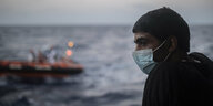 Ein Mann blickt auf das Meerim Hintergrund ein Rettungsschiff