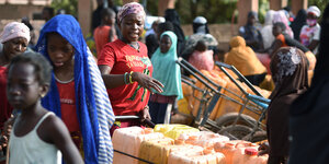 Frauen kaufen Wasser eines privaten Anbieters auf einem Markt