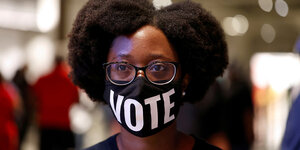 Eine Frau trägt eine Mundschutzmaske, auf die das Wort VOTE (Wähle) auf gedruckt ist
