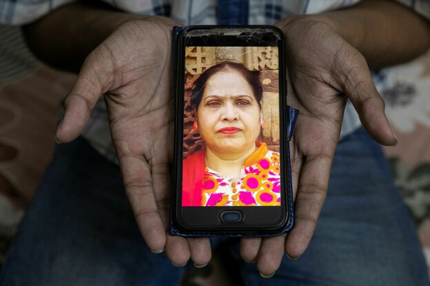 Eine Person zeigt ein Mobiltelefon mit einem Bild einer Frau.