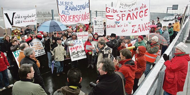 Menschen mit Transparenten demonstrieren auf einer Überführung.