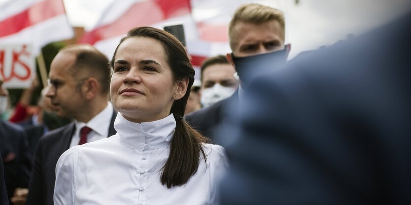 Potrait von Swetlana Tichanoeskaja, im Hintergrund sieht man weiß-rote Fahnen