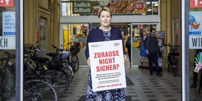 Familienministerin Giffey mit dem Plakat vor einem Supermarkt