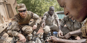 Ein deutscher Bundeswehr-Ausbilder repariert mit einem Soldaten aus Mali ein Militärfahrtzeug.