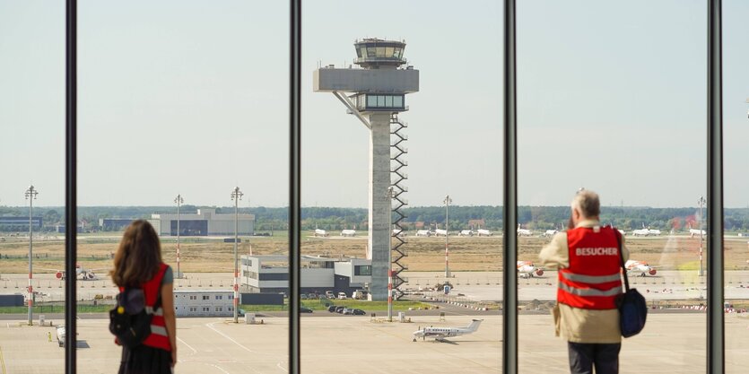 ein Mann und eine Frau schauen auf das Rollfeld des neuen Berliner Flughafen