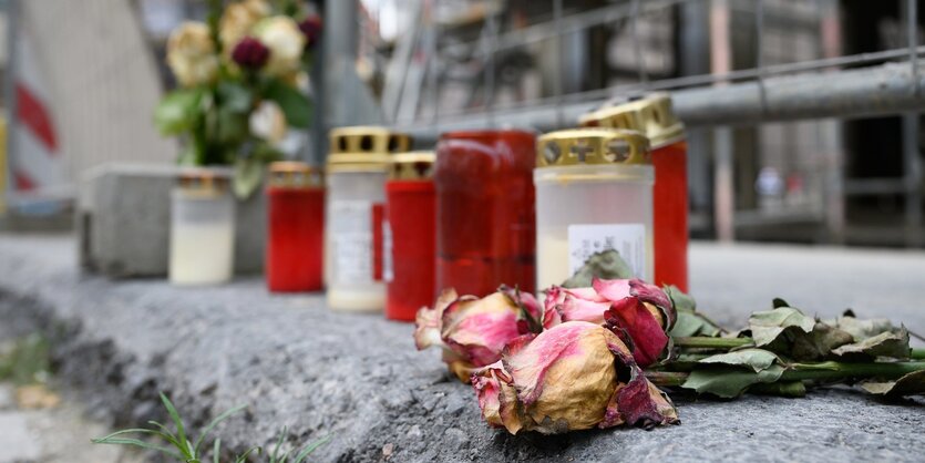 Blumen und Kerzen liegen auf einem Bordstein