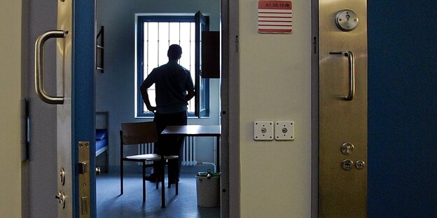 Ein Häftling steht in seiner Zelle und schaut aus dem fenster