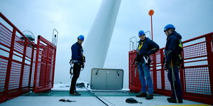 Drei Männer stehen auf der Plattform eines Offshore-Windparks.