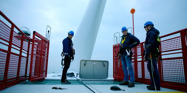 Drei Männer stehen auf der Plattform eines Offshore-Windparks.