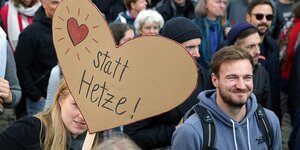 Menschen demonstrieren mit einem herzförmigen Plakat, auf dem Herz statt Hetze geschrieben steht