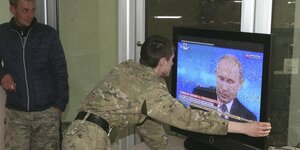 Ukrainische Separatisten schauen sich Putin im russischen Fernsehen an.