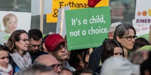 Menschen halten auf einer Demonstration ein Schild mit der Aufschrift "It's a child, not a choice"