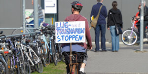 eine Frau fährt mit einem Protestschild Fahrrad