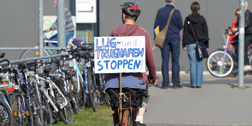 eine Frau fährt mit einem Protestschild Fahrrad